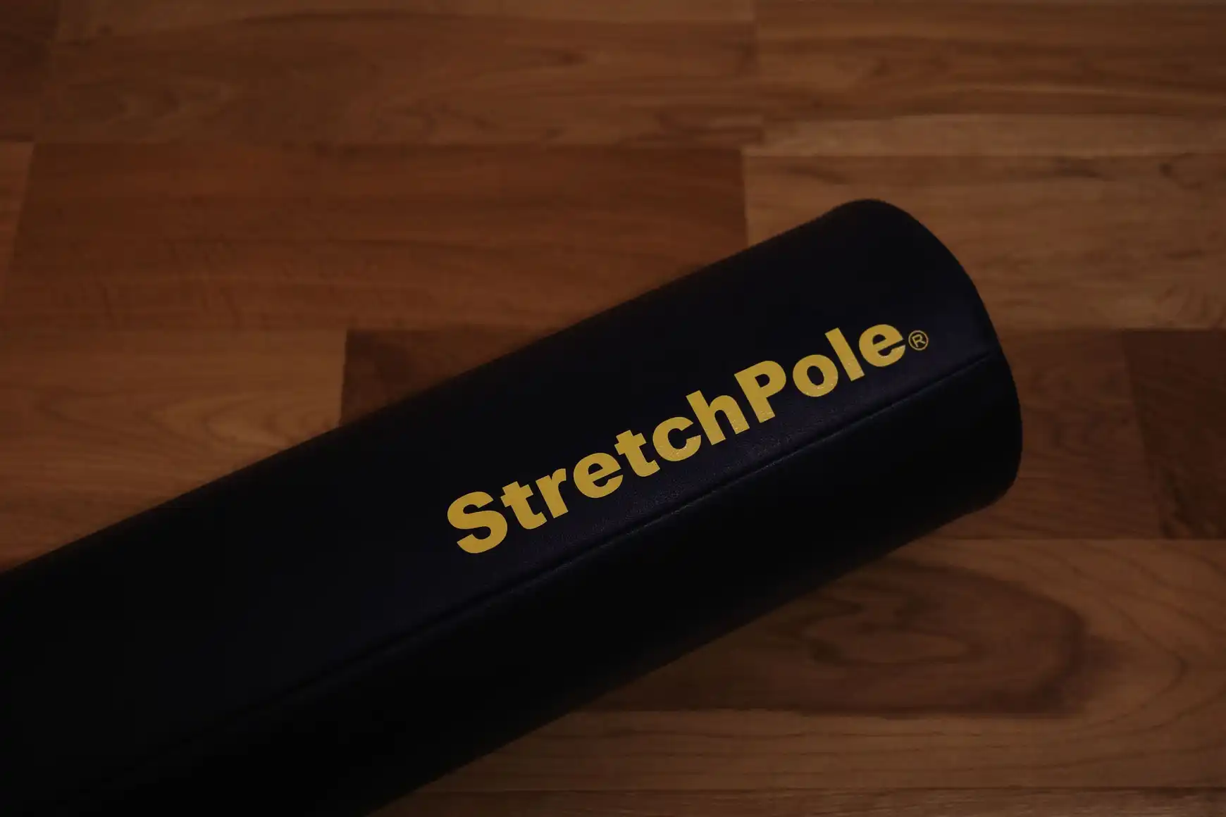 フローリングに置いたストレッチポールEX（ネイビー）の端。金色のStretchPoleロゴが見える
